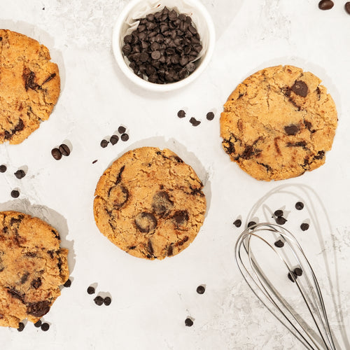 Golden cookies studded with dark and milk chocolate chunks, surrounded by loose chocolate chips.