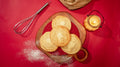 Four pale, soft-baked white chocolate cookies on a wooden board, dusted with icing sugar.